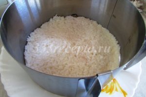 <p>Когда рис немного остыл, начинаем собирать торт. Удобнее всего это делать в форме без дна, установленной на тарелку. На дно формы выкладываем ровный слой риса.</p>
